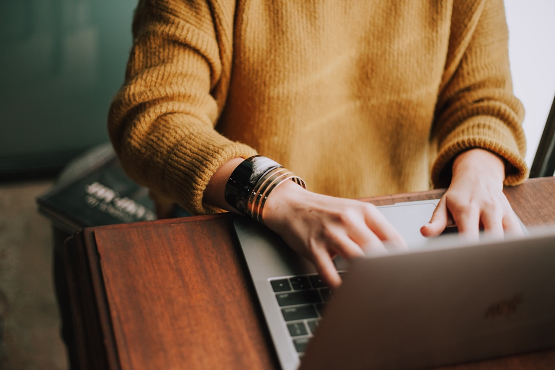 A person in a yellow sweater typing on their laptop to find out more about a request for proposal (RFP)